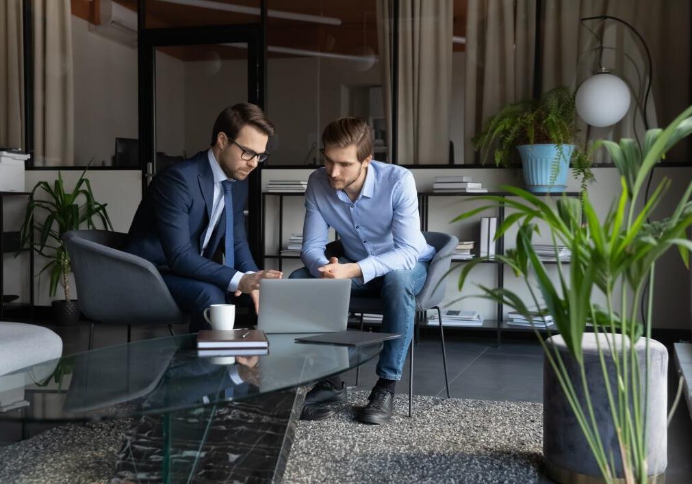 Two men discussing work on a laptop.